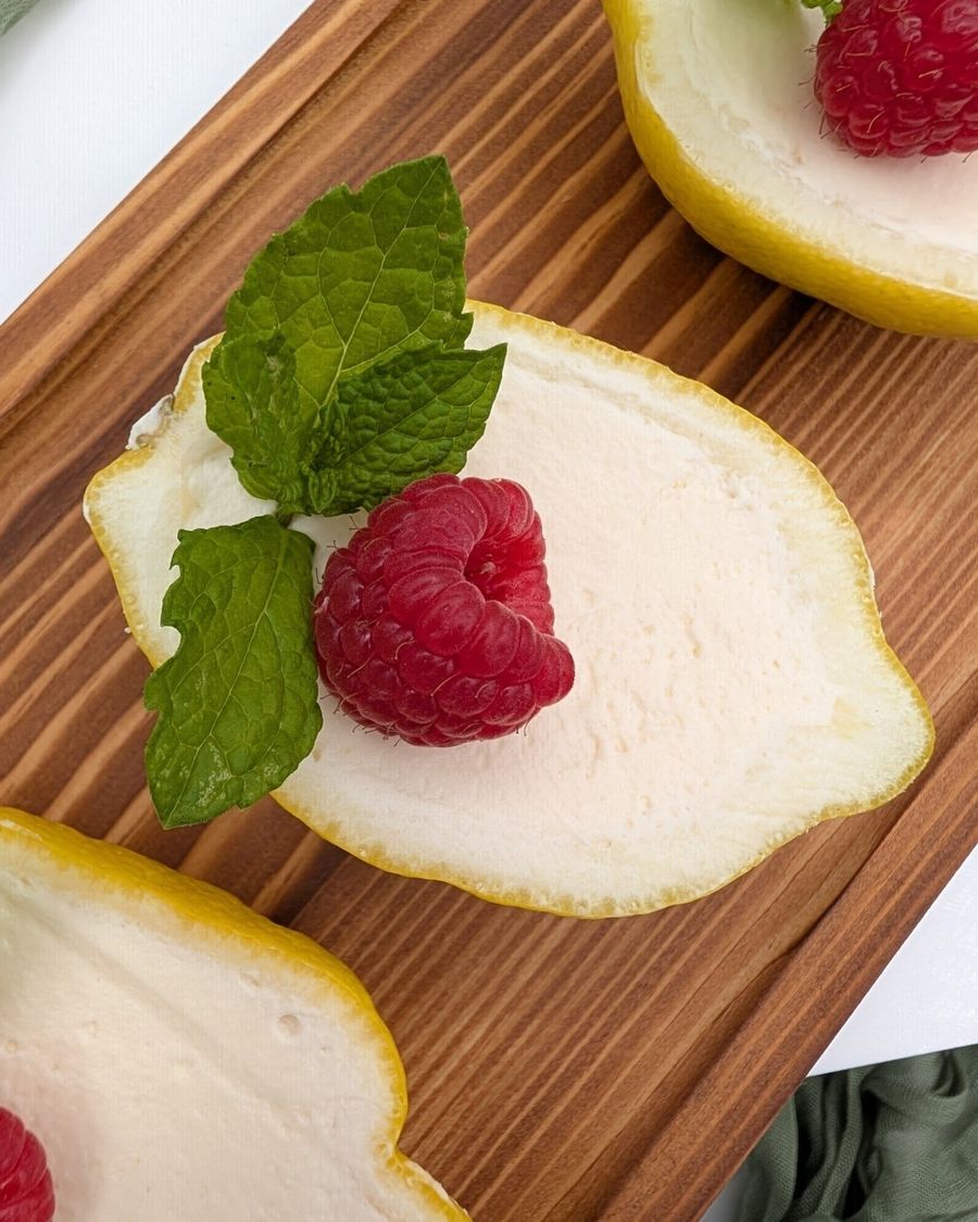 Lemon cheesecake served in a lemon half with raspberry and mint